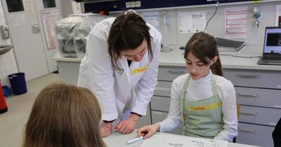 Eine Wissenschaftlerin und eine Schülerin schauen auf ein Blatt Papier. 