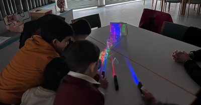 Kinder halten Taschenlampen auf Prismen, um das Licht zu brechen