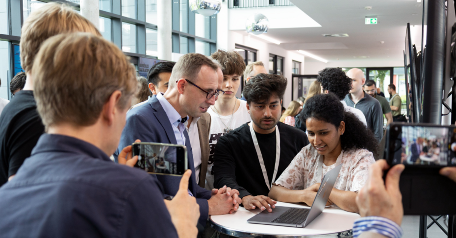 Menschen in einem Foyer, einige erklären anderen ihr Projekt