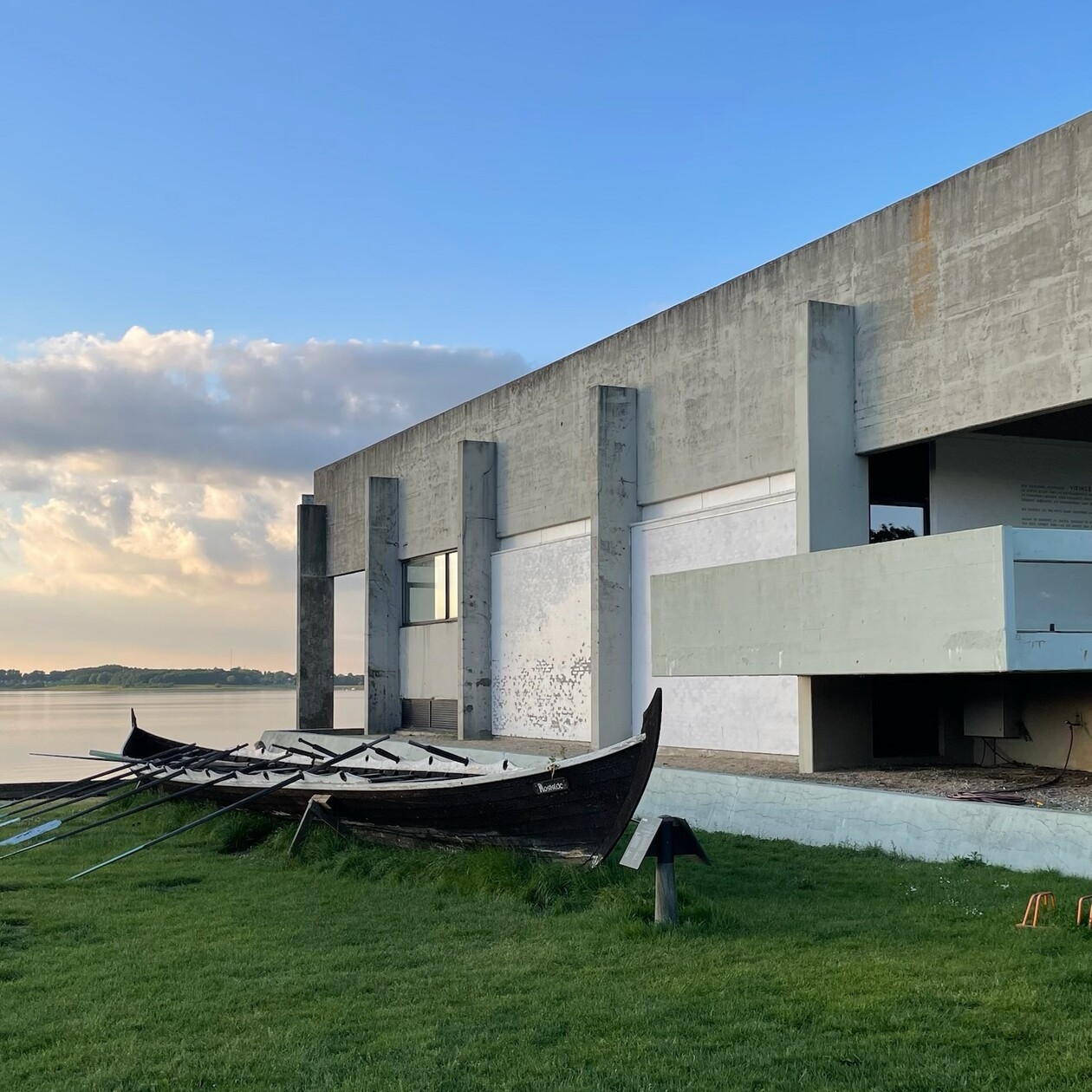 Betonhaus Verwahrlostes Betonhaus von außen und ein Boot liegt auf dem Gras