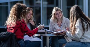Vier Studentinnen sitzen an einem Tisch zusammen.