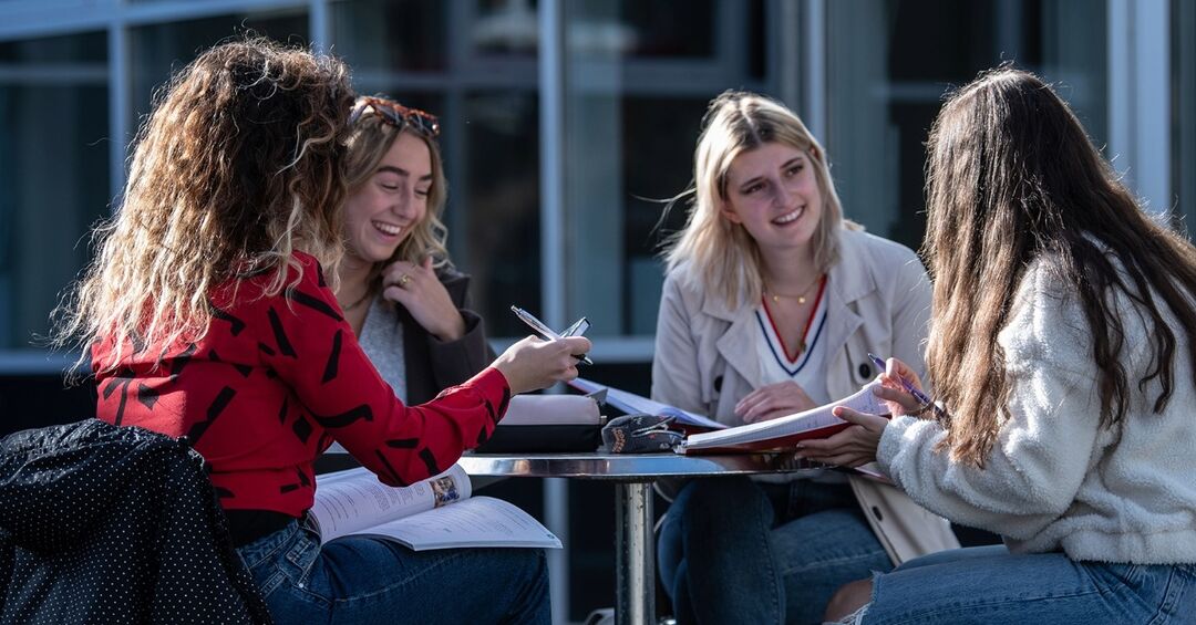 Vier Studentinnen sitzen an einem Tisch zusammen.