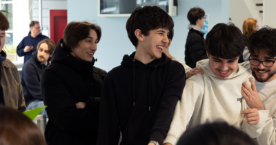 Vier junge Teilnehmer lachen herzlich gemeinsam und umarmen sich.