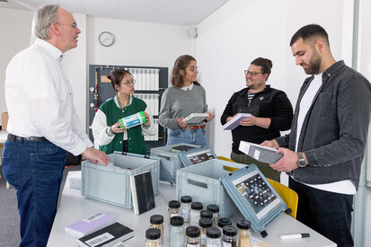 Studierende 5 Personen stehen an einem Tisch unterhalten sich