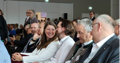 Eine Frau spricht mit einem Mann während sie im Publikum sitzen.