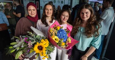 Vier junge Frauen stehen zusammen und halten Blumensträuße in den Händen.