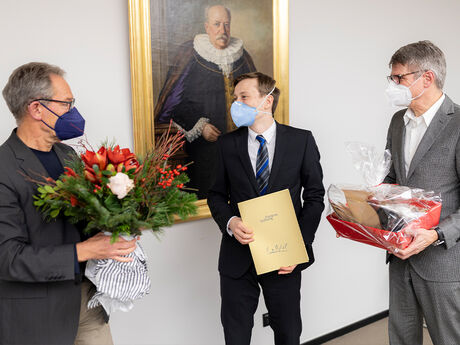 Prof. Dr. Klaus-Peter Wolf-Regett (links, stellvertretender Vorsitzender Possehl-Stiftung) übergibt Blumen und Max Schön den Präsentkorb mit regionalen Spezialitäten. Foto: Agentur 54°