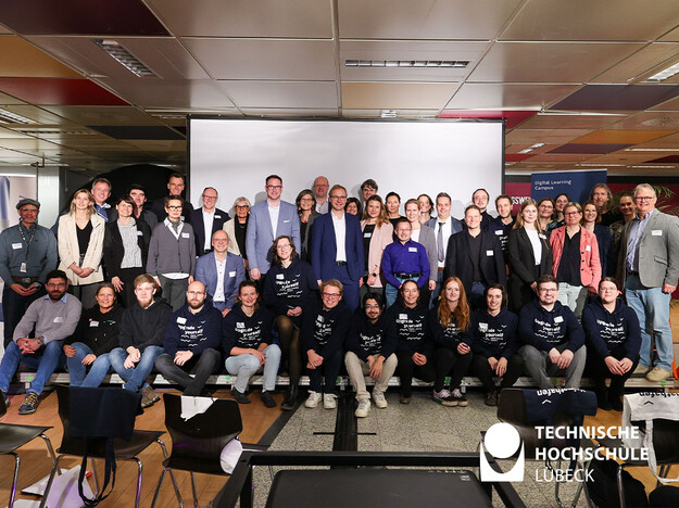 Gruppenfoto der Teilnehmenden Zirka 60 Leute sitzen oder stehen für das Foto