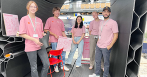 Fünf Menschen in rosa T-Shirts lächeln in die Kamera
