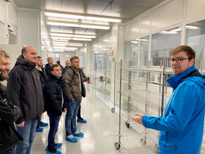 Exkursion zur Firma Vishay Thomas Alms, Student Physikalische Technik, der gleichzeitig Werkstudent bei Vishay ist, erklärt seinen Kommiliton*innen die Produktion