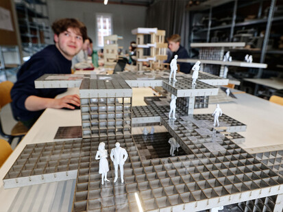 Bild zeigt Modellhaus und im Hintergrund einen Studenten