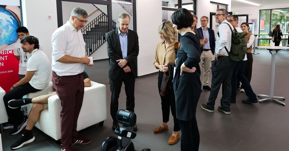 Gruppe betrachtet mobilen Roboter im Hochschulfoyer