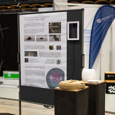 Plakatwand und 3d gedrucktes Bauteil aus Lehm