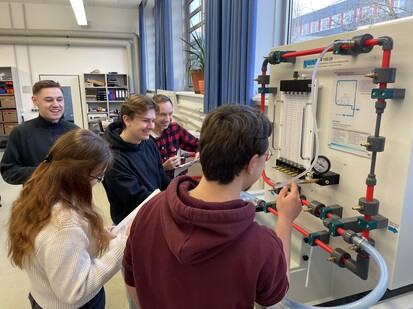 Messung Druckverluste Fünf Studierende stehen an einer Wand mit Rohren und messen