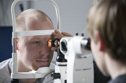 Person leuchtet mit einer Lampe ins Auge