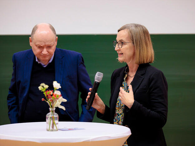 Gesprächsrunde ein Mann links eine Frau rechts, die ein Mikrofon hält