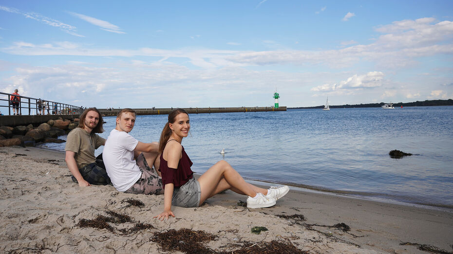 Studierende sitzen am Strand in Travemünde