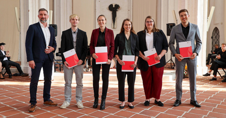Förderpreisträgerinnen und -preisträger der TH Lübeck mit Urkunden auf Bühne
