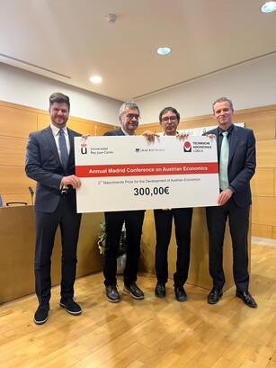 Four men hold up a large ceremonial prize check for 300,00€.