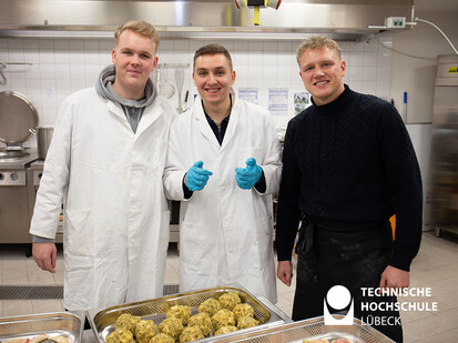 Thema weihnachtliches Essen Drei Personen posieren für die Kamera und vor ihnen liegen Knödel