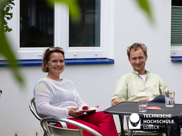 Bergfest beim Mentoringprogramm Zwei Personen sitzen an einem Tisch und eine hat ein Stück Kuchen in der Hand