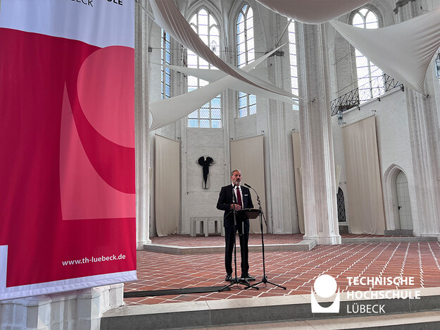 Lübecks Stadtpräsident erhofft sich, dass viele Studierende nach dem Studium in Lübeck bleiben Lübecks Stadtpräsident steht am Rednerpult der Sankt Petri Kirche
