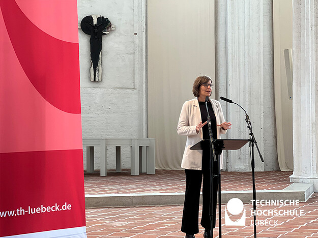 Begrüßung und Ermutigung zur Gremienarbeit der Erstsemester von der TH Lübeck Präsidentin TH Lübeck Präsidentin steht am Rednerpult der Sankt Petri Kirche