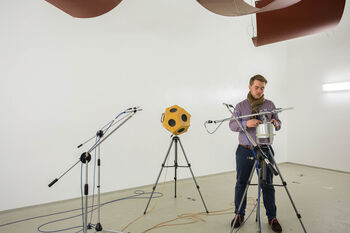 Hörakustik-Student bereitet im Hallraum der TH Lübeck eine Messung der Schallabsorption mit Dodekaeder-Lautsprecher und Mikrofonen vor.