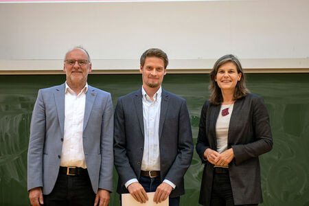 Preisübergabe: Preisträger, Präsidentin und Vizepräsident stehen im Hörsaal vor einer Tafel.