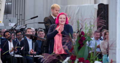 Ein junger Mann und eine junge Frau stehen klatschend auf der Bühne.
