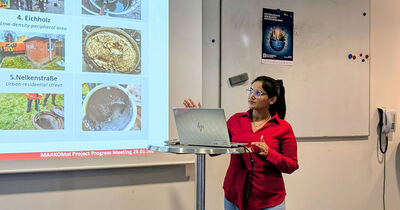 Eine Frau in rotem Hemd zeigt Ergebnisse in einer Power Point