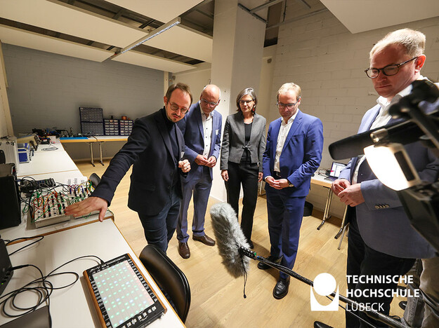 Ausstellung Professor Nicola Hein Gäste stehen um Ausstellungsobjekt herum und bekommen Erklärung