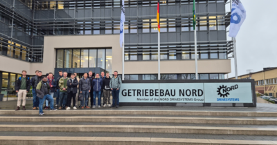 Besuchergruppe steht vor dem Firmengebäude von Getriebebau Nord.