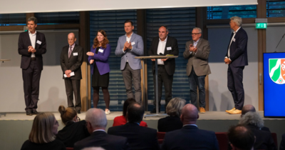 Sieben Personen stehen auf der Bühne der neunten Konferenz.