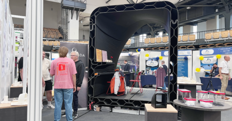 Menschen neben einem großen schwarzen 3D gedruckten Modell 
