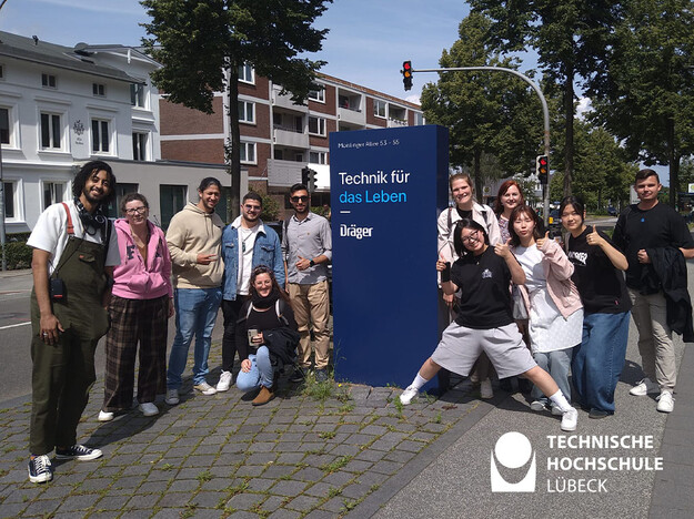 Studierende stehen um ein Schild von Dräger herum