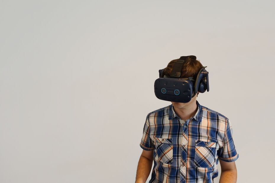 Person hat ein VR-Headset auf und steht vor einem weißen Hintergrund