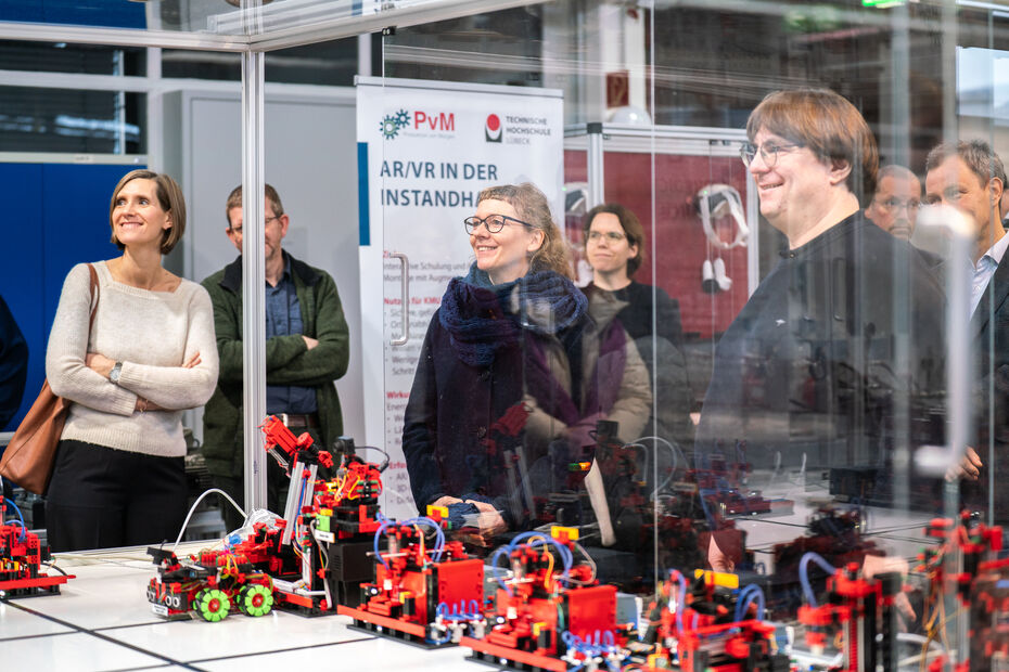 Personen stehen freudig vor technischen Demonstratoren