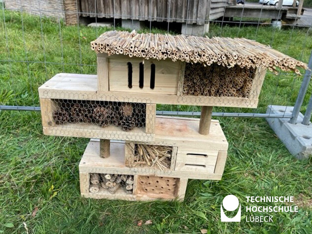 Das Bild zeigt ein vier Insektenhotel mit mehreren versetzten Ebenen