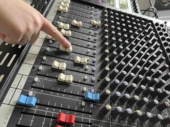 Hand eines Studierenden beim Justieren der Fader an einem großen Mischpult im Tonstudio der TH Lübeck.