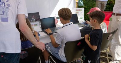 th_luebeck_juniorcampus_minecraft Kinder sitzen und stehen vor Laptops unter einem Zelt