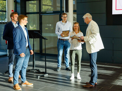 Preisübergabe Mann übergibt einer Frau eine Urkunde