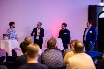 KI Diskussionsrunde Vier Männer stehen nebeneinander auf Podium und diskutieren