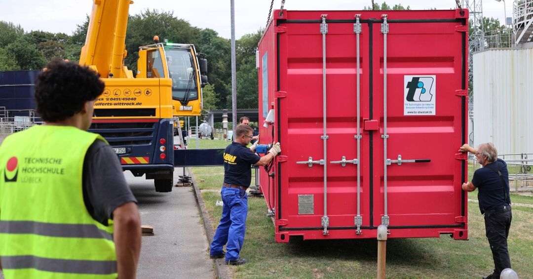 Menschen stehen um einen roten Container herum