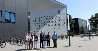 Ein Gruppenfoto vor einem grauen modernen Gebäude
