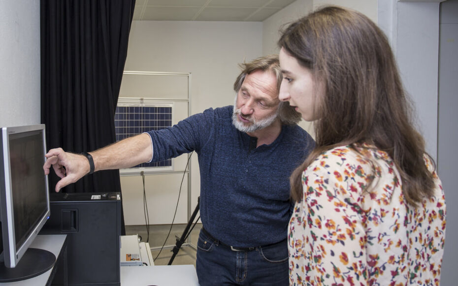 Ein Professor erklärt einer Studierenden einen Zusammenhang an einem Monitor im Labor eines Studiengangs