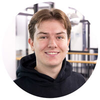 Ein junger Mann mit kurzen braunen Haaren lacht in die Kamera