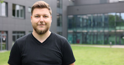 Mann mit braunen kurzen Haaren lächelt in die Kamera