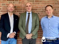 TH Lübeck Dekan und Professor stehen neben Gastwissenschaftler und lächeln