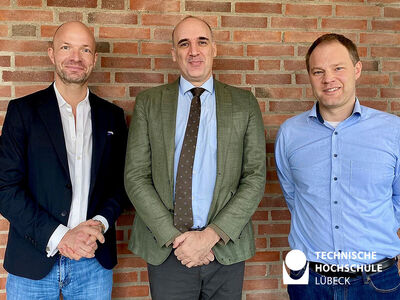 TH Lübeck Dekan und Professor stehen neben Gastwissenschaftler und lächeln